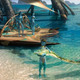 A Na'vi child holds the head of a big lizard on the beaches of Pandora in this concept art from Avatar 2.